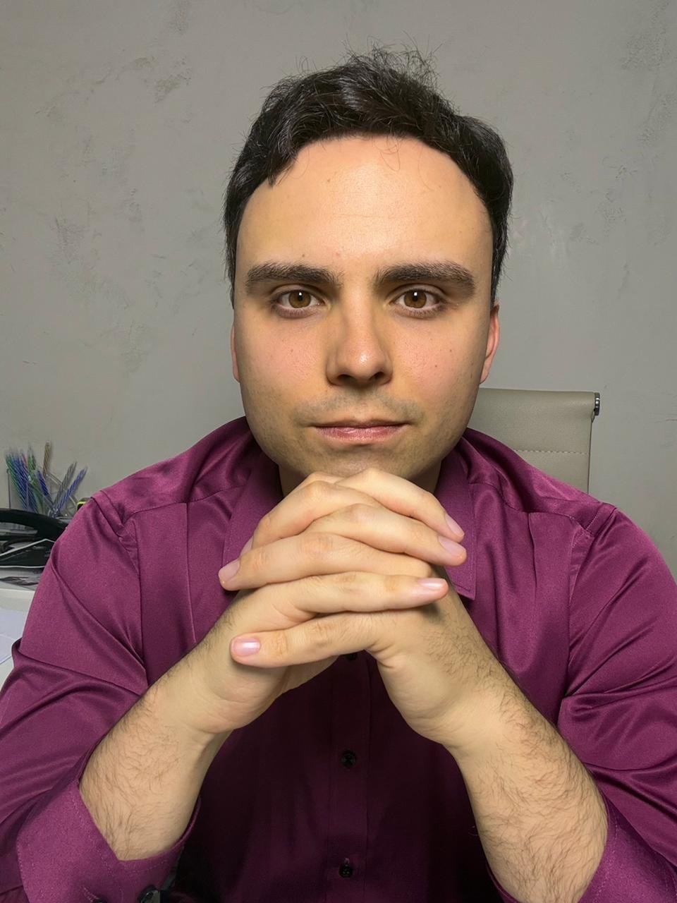 Dr. Lucas Batistuzzo com as mãos sob o queixo, em atitude de escuta